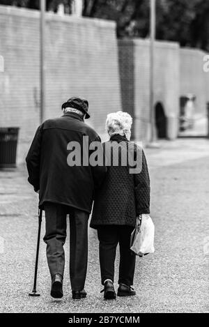 Prise de vue verticale en niveaux de gris d'un vieux couple romantique qui se tient à pied mains Banque D'Images