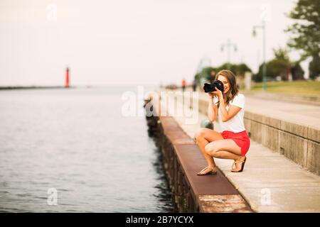 photographe jeune femme - prendre des photos du coucher du soleil au large du lac Banque D'Images