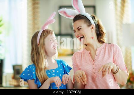 jeune mère et enfant joyeux dans les oreilles de lapin de pâques à la maison moderne dans la journée ensoleillée de printemps ayant du temps amusant. Banque D'Images