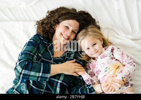 Vue en grand angle de la mère et de la fille sur les pyjamas couchés sur le lit Banque D'Images