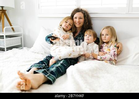 Femme assise avec ses filles au lit Banque D'Images