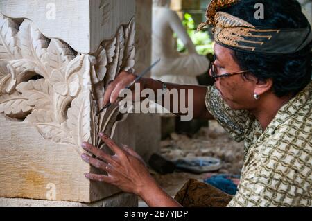 Un artisan balinais à l'œuvre de la sculpture d'une statue d'un bloc de pierre Banque D'Images