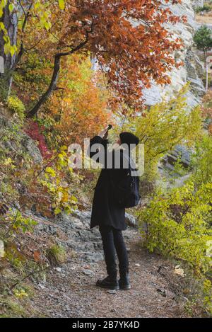 Jeune femme photographiant avec un smartphone dans la forêt d'automne Banque D'Images