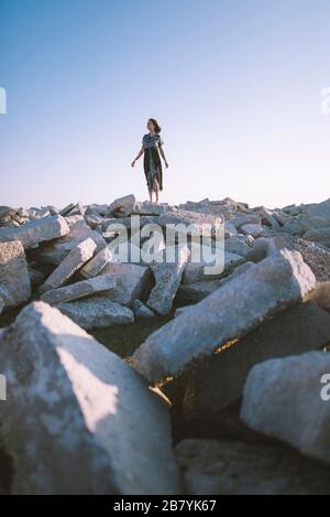 Jeune femme en robe debout sur des rochers Banque D'Images