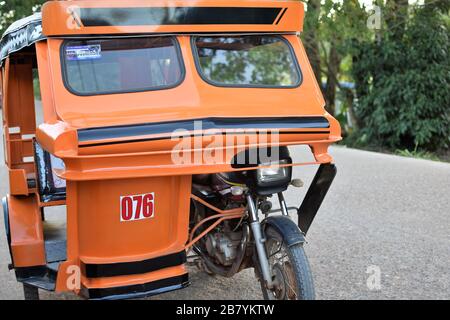 Un tricycle orange est stationné sur le côté de la route à Coron, Palawan aux Philippines Banque D'Images