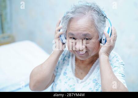 Asian senior ou âgée vieille dame patient utiliser l'oreille tout en se coucher et heureux sur le lit dans le service d'hôpital de soins infirmiers : sain fort concept médical Banque D'Images