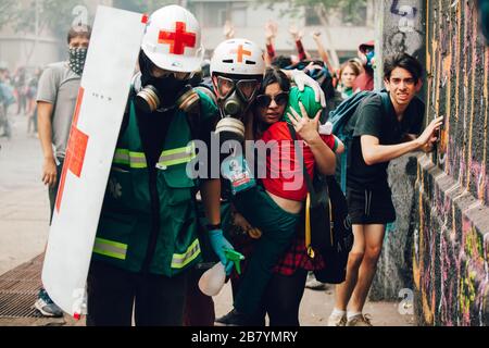 SANTIAGO, CHILI-8 NOVEMBRE 2019 - les volontaires de la Croix-Rouge utilisent des boucliers pour protéger les civils contre les projectiles de la police et des manifestants lors des manifestations ag Banque D'Images