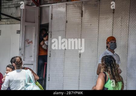 Caracas, Venezuela. 18 mars 2020. Les travailleurs d'un magasin local se promenant à travers les portes pendant que la police ferme toutes les stablentions.après 3 jours de quarantaine décrétés par le gouvernement du président Nicolas Maduro, jusqu'à présent le chiffre de 36 personnes confirmées être infectées par COVID-19 reste. Les résultats sont attendus de plus de 120 échantillons envoyés par l'institut d'hygiène. Les agences de sécurité continuent de fermer les entreprises et d'essayer de garder les gens dans leur foyer pour empêcher le virus de se propager davantage. Crédit: SOPA Images Limited/Alay Live News Banque D'Images