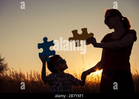 Mère et fils jouant au parc à l'heure du coucher du soleil. Les gens qui s'amusent sur le terrain. Le concept de l'enfant est prêt à aller à l'école. Banque D'Images