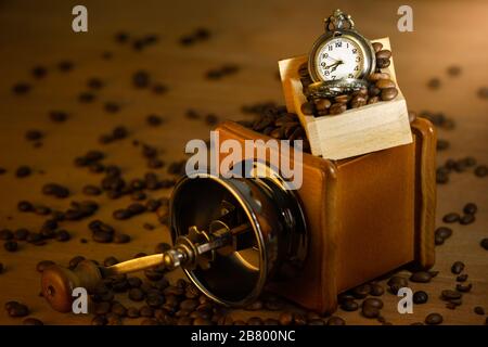 Grain de café et montre de poche. Meuleuse manuelle sur table en matinée. Concept de café. Banque D'Images