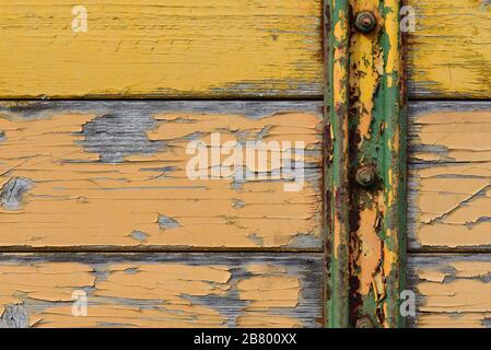 Gros plan et détail grené, texture et fond de lamelles en bois désalées avec de la peinture jaune qui s'écaille et un vieux rail en métal Banque D'Images