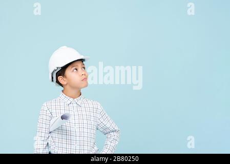 Doute ingénieur garçon avec casque blanc regardant vers le haut isolé sur fond bleu clair Banque D'Images