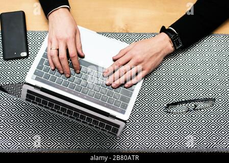 Gros plan sur les mains d'un homme tapant sur un clavier d'ordinateur portable. Image recadrée d'un jeune homme travaillant sur son ordinateur portable dans un café. Banque D'Images