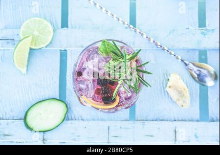 Vue de dessus du cocktail de mojito de baies sur le comptoir de bar en bois bleu - tropical, boissons, fête et concept - se concentrer sur le verre Banque D'Images