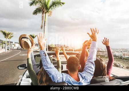 Heureux amis avec les mains jusqu'à s'amuser dans une voiture de location convertible en vacances d'été - jeunes gens enjoint les vacances de voyage - concept de style de vie de jeunesse - Banque D'Images