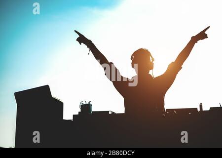 Silhouette de dj mélangeant l'extérieur avec les mains au coucher du soleil - Portrait de Disc jockey jouant de la musique vinyle de style ancien pour les gens sur la plage partie - plaisir, sume Banque D'Images