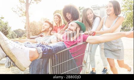 Jeunes millénaires les gens qui font de la course avec un panier - heureux amis fous s'amuser avec des chariots dans le parking - style de vie des jeunes et concept de fête - FO Banque D'Images