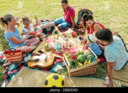 Vue de dessus des familles multiraciales heureuses faisant pique-nique dans le parc naturel extérieur - jeunes parents s'amuser avec les enfants en été - nourriture, week-end frv Banque D'Images