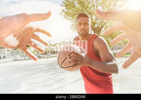 Joueur de panier multiracial jouant un jeu dans le camp urbain de quart de rue en plein air avec l'éclairage arrière - mains de l'athlète essayant de prendre le ballon de son oppo Banque D'Images