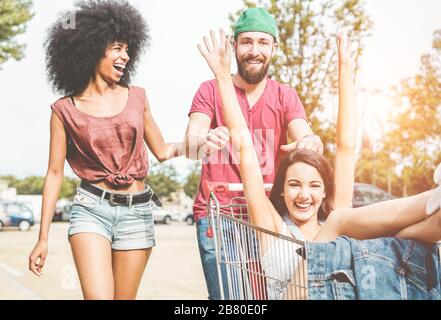 Jeunes millénaires les gens qui font de la course avec un panier - heureux amis fous s'amuser avec des chariots dans le parking - style de vie des jeunes, amitié, bonheur Banque D'Images