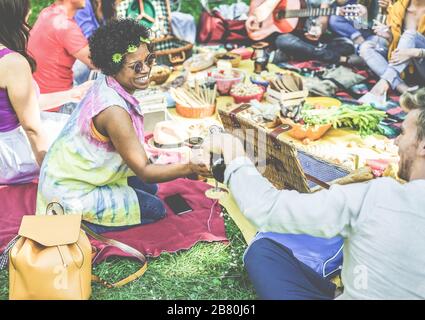 Groupe d'amis faisant pique-nique et boire sur le parc de la ville en plein air - jeunes gens manger un repas barbecue pour le déjeuner dans l'arrière-cour - Focus sur la fille africaine de cheveux - y Banque D'Images