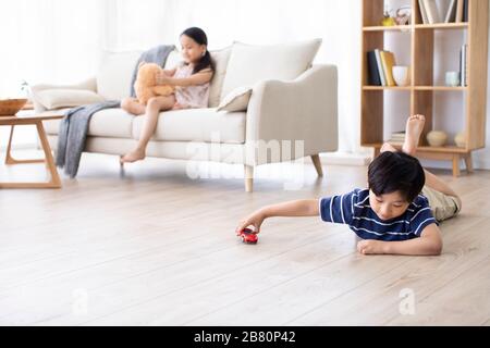 Bonne sœur chinoise jouant avec des jouets dans le salon Banque D'Images