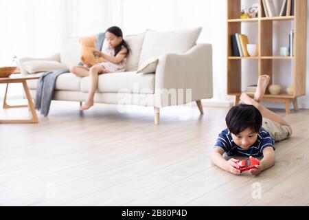 Bonne sœur chinoise jouant avec des jouets dans le salon Banque D'Images