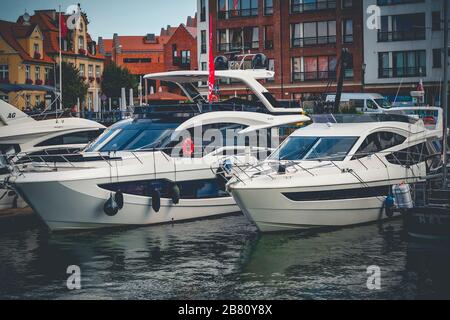 Yachts modernes amarrés dans le port de plaisance de Gdansk sur la rivière New Motlawa à Gdansk, Pologne avec de vieux bâtiments en arrière-plan Banque D'Images