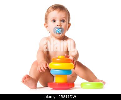 Vue avant de l'adorable enfant avec sucette en bouche jouant avec un jouet empilable. Anneaux colorés doux pour les tout-petits sur un cône en plastique. Isolé sur blanc s Banque D'Images