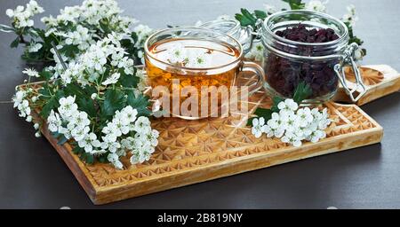 Tisand thé d'arthorn à base de plantes bourgeons autour des branches florales et un pot avec des baies sur planche à découper en bois, gros plan, espace de copie, santé du coeur et h Banque D'Images