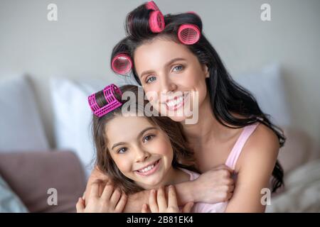 Maman et fille avec des bigoudis à l'air heureux Banque D'Images