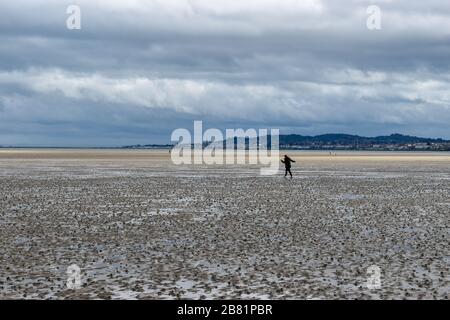 Une femme qui maintient des distances sociales marchant dehors sur la plage de Dublin, en Irlande Banque D'Images