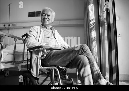 heureux et content un vieil homme asiatique assis dans une chaise roulante dans une maison de soins infirmiers ou un service hospitalier, noir et blanc Banque D'Images