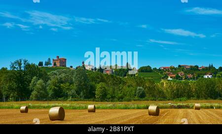 Grands rouleaux de paille allongé sur un champ de mown après récolte du grain - en août près de la ville de Grinzane Cavour dans la province Cuneo, région Piémont, nord Banque D'Images