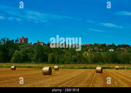 Grands rouleaux de paille allongé sur un champ de mown après récolte du grain - en août près de la ville de Grinzane Cavour dans la province Cuneo, région Piémont, nord Banque D'Images