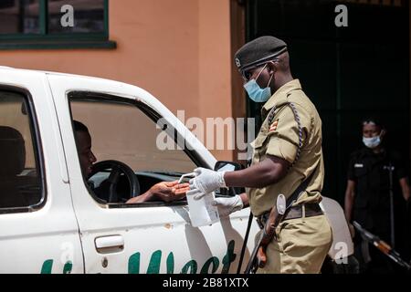 Kampala, Ouganda. 18 mars 2020. Un policier désinfecte les mains d'un conducteur à Kampala, en Ouganda, le 18 mars 2020. Le président ougandais Yoweri Museveni a annoncé mercredi une série de nouvelles mesures pour lutter contre la nouvelle maladie du coronavirus (COVID-19) dans le pays de l'Afrique de l'est une fois qu'elle a été brisé. L'Ouganda n'a pas encore enregistré de cas de COVID-19, mais le ministère de la santé a déclaré qu'il est confronté à un risque élevé. Crédit: Hajarah Nalwadda/Xinhua/Alay Live News Banque D'Images