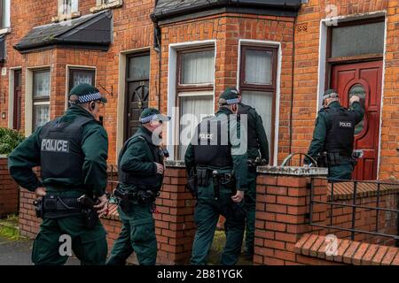 Les officiers du PSNI TSG entrent dans une propriété lors d'une recherche dans une rue mitoyenne au large de la route Crumlin dans la région de Shankill au nord de Belfast. La recherche faisait partie de l'opération Pangea qui vise la vente en ligne de médicaments et de dispositifs médicaux contrefaits et illicites. Banque D'Images