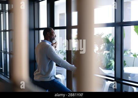 Homme africain américain regardant à l'extérieur et ayant un appel téléphonique Banque D'Images