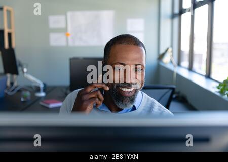 Homme africain américain travaillant au bureau et ayant un appel téléphonique Banque D'Images