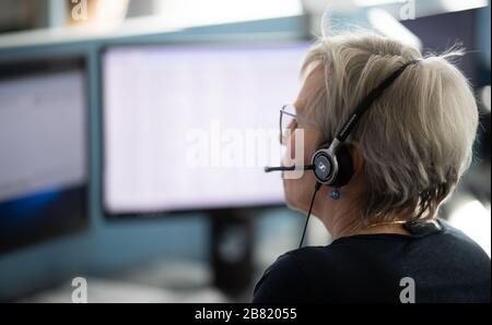 Hambourg, Allemagne. 19 mars 2020. Une femme fait un appel téléphonique dans un échange téléphonique du service d'appel du Kassenärztliche Vereinigung Hamburg pour la ligne d'assistance médicale ''116117''' du service médical en ligne. Un porte-parole de l'Agence allemande de presse a déclaré que mercredi, il y avait eu une diminution de plus de 18 000 appels pour la première fois en cinq jours. Crédit: Daniel Reinhardt/dpa/Alay Live News Banque D'Images