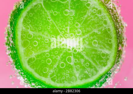 agrumes à la chaux dans l'eau, sous l'eau. concombre de citron vert avec bulles. agrumes juteux gros plan, macro sélective focus. Banque D'Images