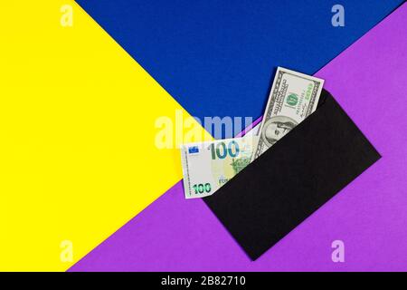 Billets en euros et en dollars américains dans une enveloppe noire sur fond de papier couleur. Enveloppe cadeau avec de l'argent comme bonus, récompense, concept d'avantages, pot-de-vin gif Banque D'Images