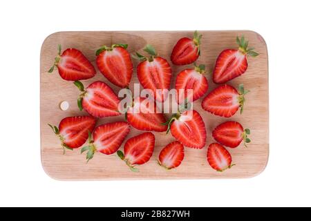 Fraises mûres fraîches coupées en moitiés disposées sur la planche de cuisine Banque D'Images