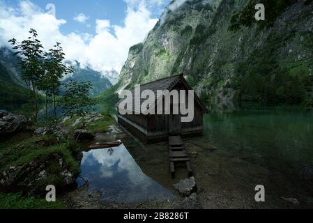 Une cabine en bois/une maison de bateau, au lac Obersee entouré de montagnes à Schoenau am Koenigssee dans les Alpes bavaroises, le parc national de Berchtesgaden, Allemagne Banque D'Images