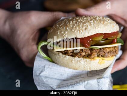 Vue rapprochée d'un hamburger de légumes quorn tenu par les mains de l'homme. Banque D'Images