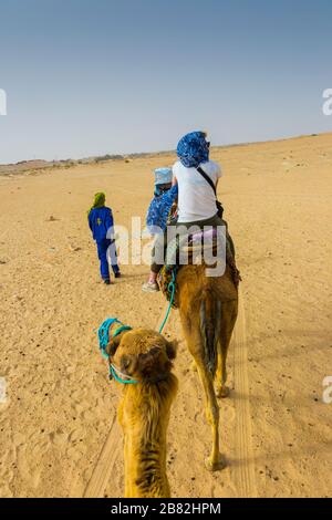 Guide de femme et de tuareg dans une promenade dromadaire dans le désert. Banque D'Images