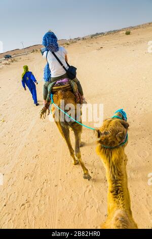 Guide de femme et de tuareg dans une promenade dromadaire dans le désert. Banque D'Images