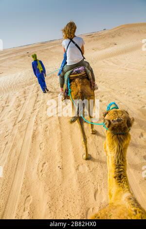 Guide de femme et de tuareg dans une promenade dromadaire dans le désert. Banque D'Images