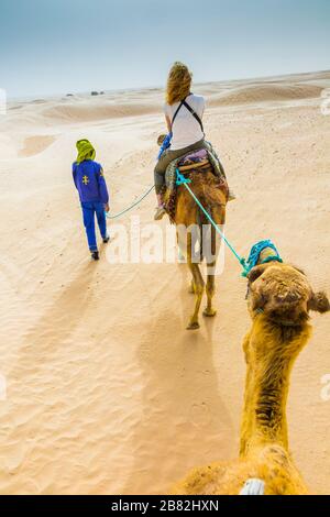 Guide de femme et de tuareg dans une promenade dromadaire dans le désert. Banque D'Images