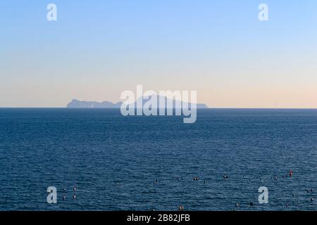L'île de Capri sur la ligne d'horizon au-dessus du golfe de Naples vue du front de mer de la ville dans une vue sur le paysage au coucher du soleil Banque D'Images